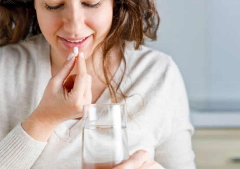 Hình ảnh người phụ nữ đang uống thuốc tây điều trị trong kinh