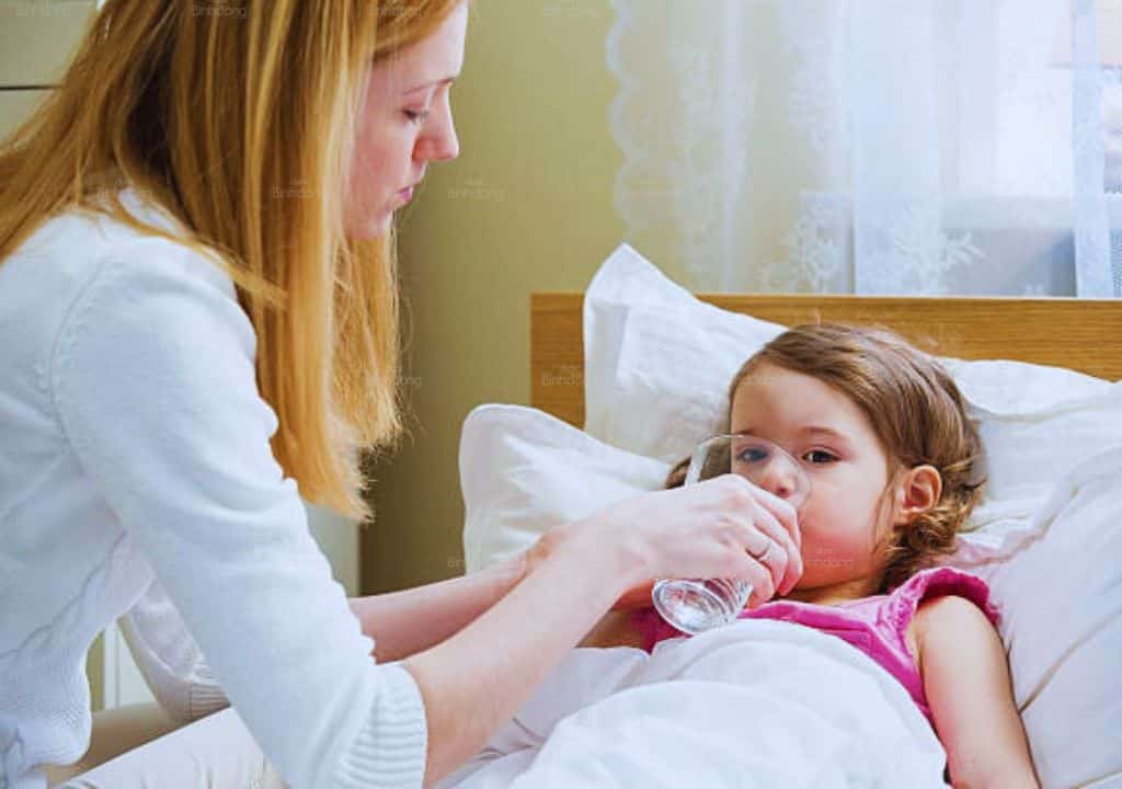 Hình ảnh người mẹ đang chăm sóc cho người con đang bị sốt đang nằm trên giường