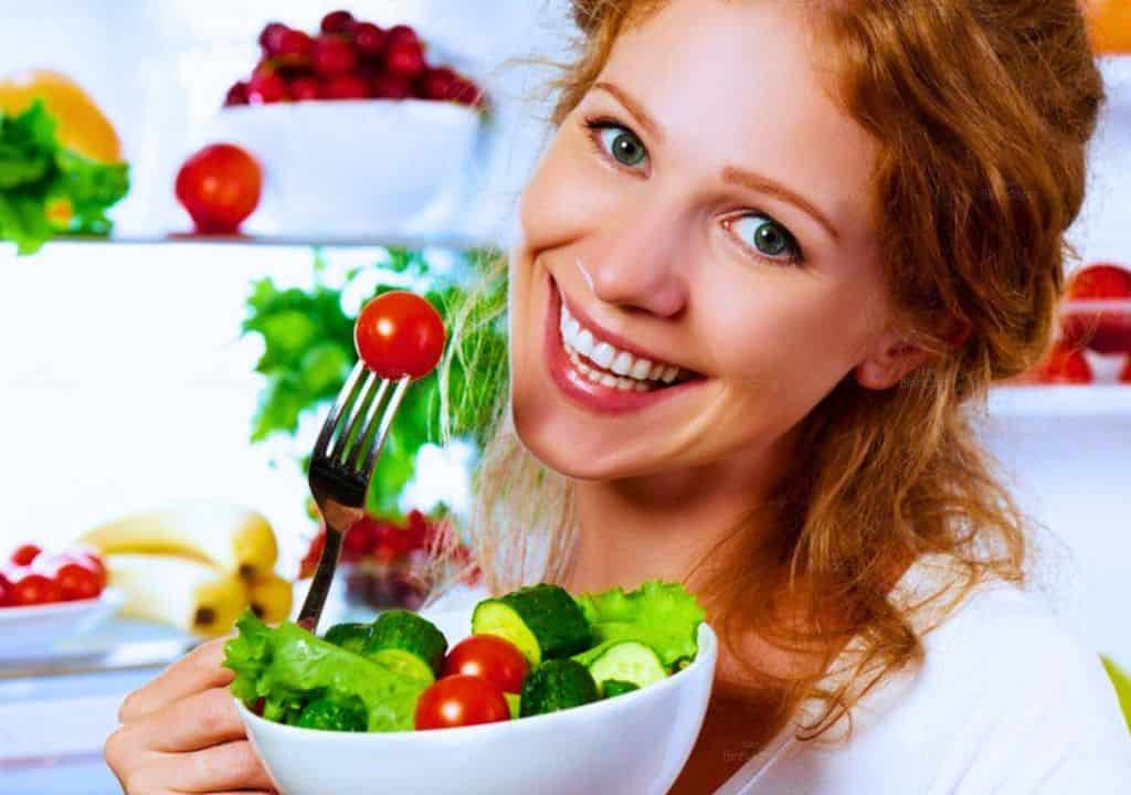 Hình ảnh người phụ nữ đang ăn rau để hỗ trợ điều trị bệnh kinh nguyệt ra ít