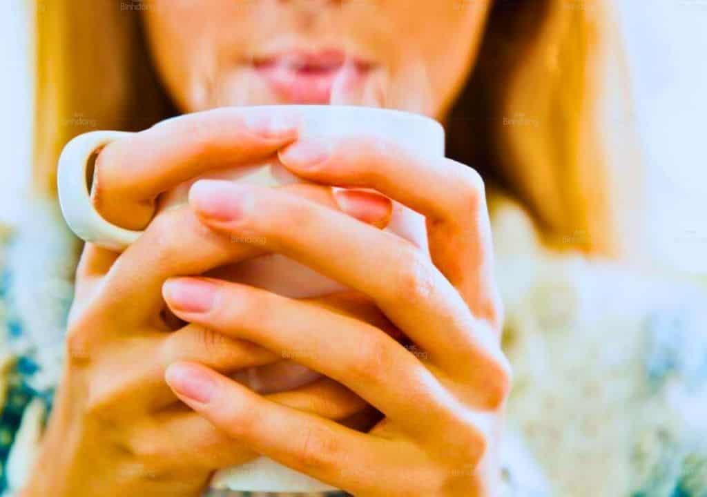 Hình ảnh người phụ nữ đang uống nước nóng để giảm đau họng