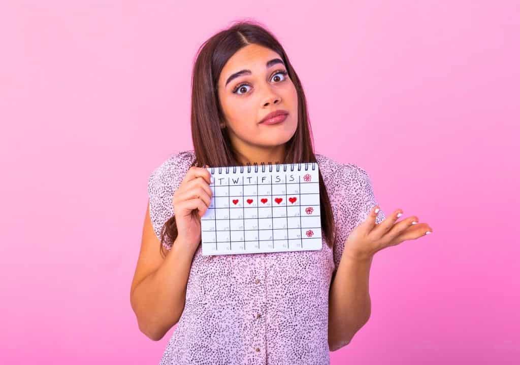 Hình ảnh người phụ nữ đang cầm tờ lịch và khó chịu do bị kinh thưa