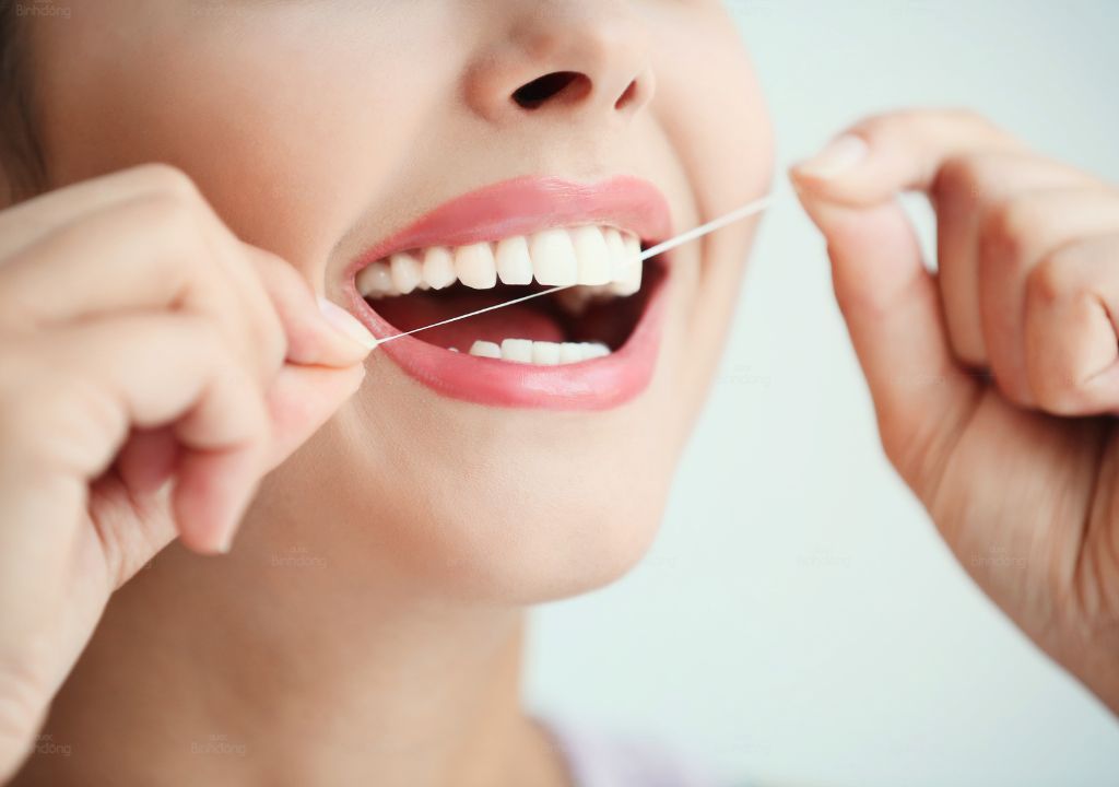 Hình chụp người phụ nữ Dùng chỉ nha khoa vệ sinh răng