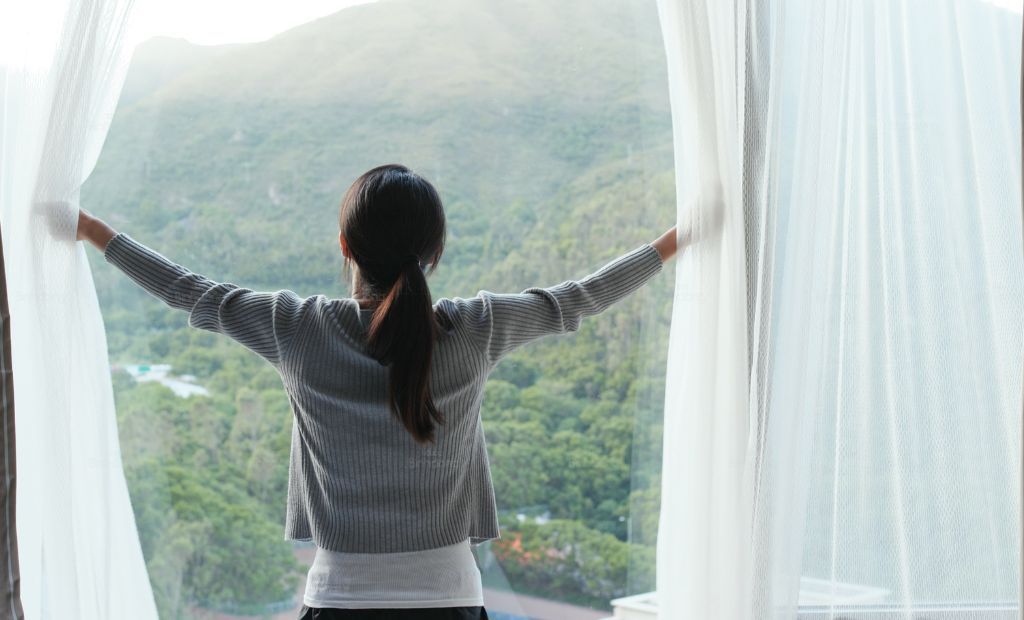 Người phụ nữ đang mở cửa sổ