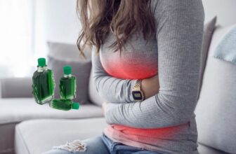 Người phụ nữ ôm bụng dưới khi đau bụng kinh và đặt chai dầu gió bên cạnh để giảm đau tạm thời.