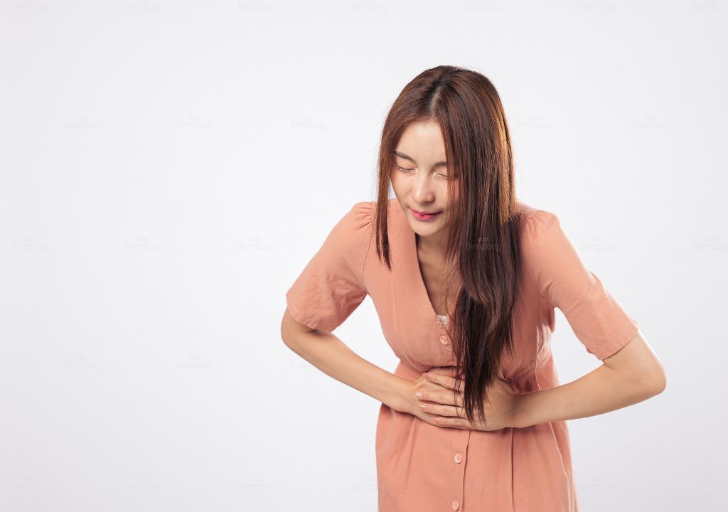Người phụ nữ ôm bụng biểu hiện đau bụng kinh và khó chịu trong kỳ hành kinh.