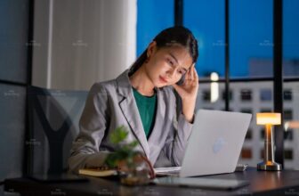 Người phụ nữ thức đêm làm việc trước laptop, mệt mỏi, gục xuống bàn do thiếu ngủ và rối loạn đồng hồ sinh học.