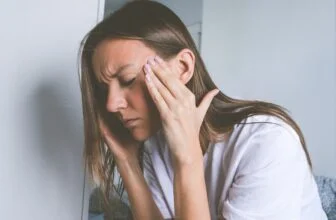 Người phụ nữ ôm vùng thái dương do đau đầu căng thẳng.