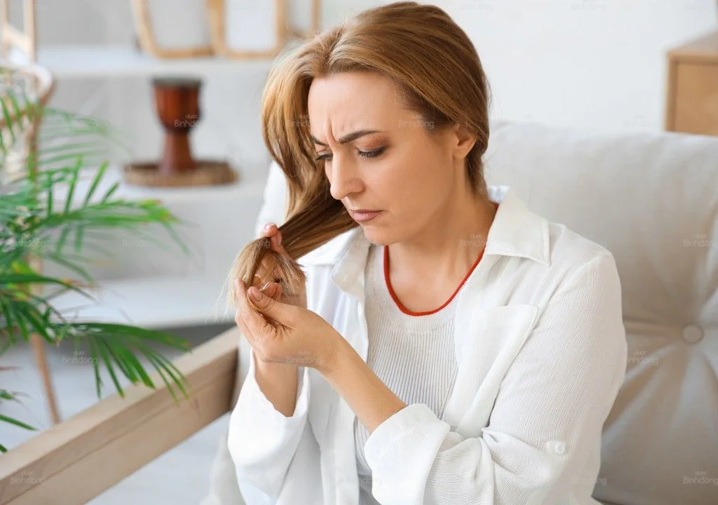 Người phụ nữ kiểm tra phần tóc khô xơ và dễ gãy rụng.