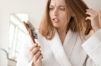 Người phụ nữ lo lắng khi thấy tóc rụng nhiều trên lược do thiếu chất.