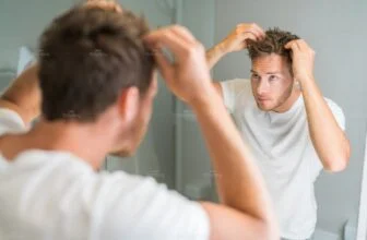 Nam giới soi gương kiểm tra tình trạng rụng tóc và tóc thưa.