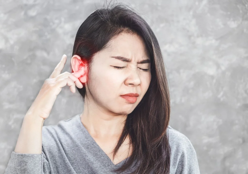 Người phụ nữ bị ù tai đưa tay chạm vào tai với biểu hiện đau khó chịu