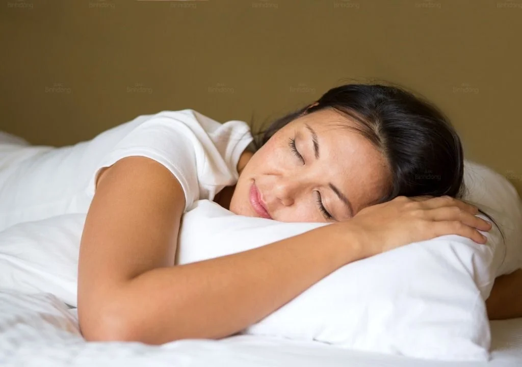 Người phụ nữ ngủ ngon trên giường, minh họa chất lượng giấc ngủ và thời lượng ngủ đủ để cơ thể phục hồi.