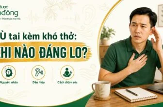 Người đàn ông Việt Nam đặt tay lên ngực và đưa tay lên tai, ngồi cạnh laptop