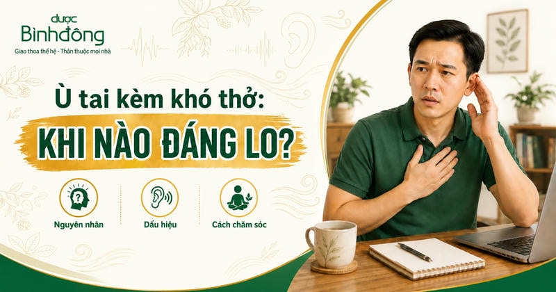 Người đàn ông Việt Nam đặt tay lên ngực và đưa tay lên tai, ngồi cạnh laptop